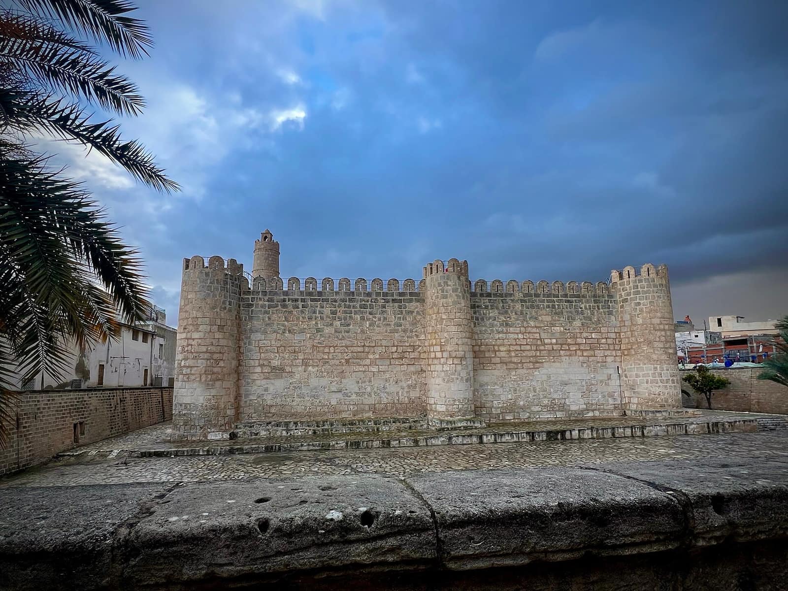 Le ribat de Sousse sous un ciel d'orage, palmier au premier plan