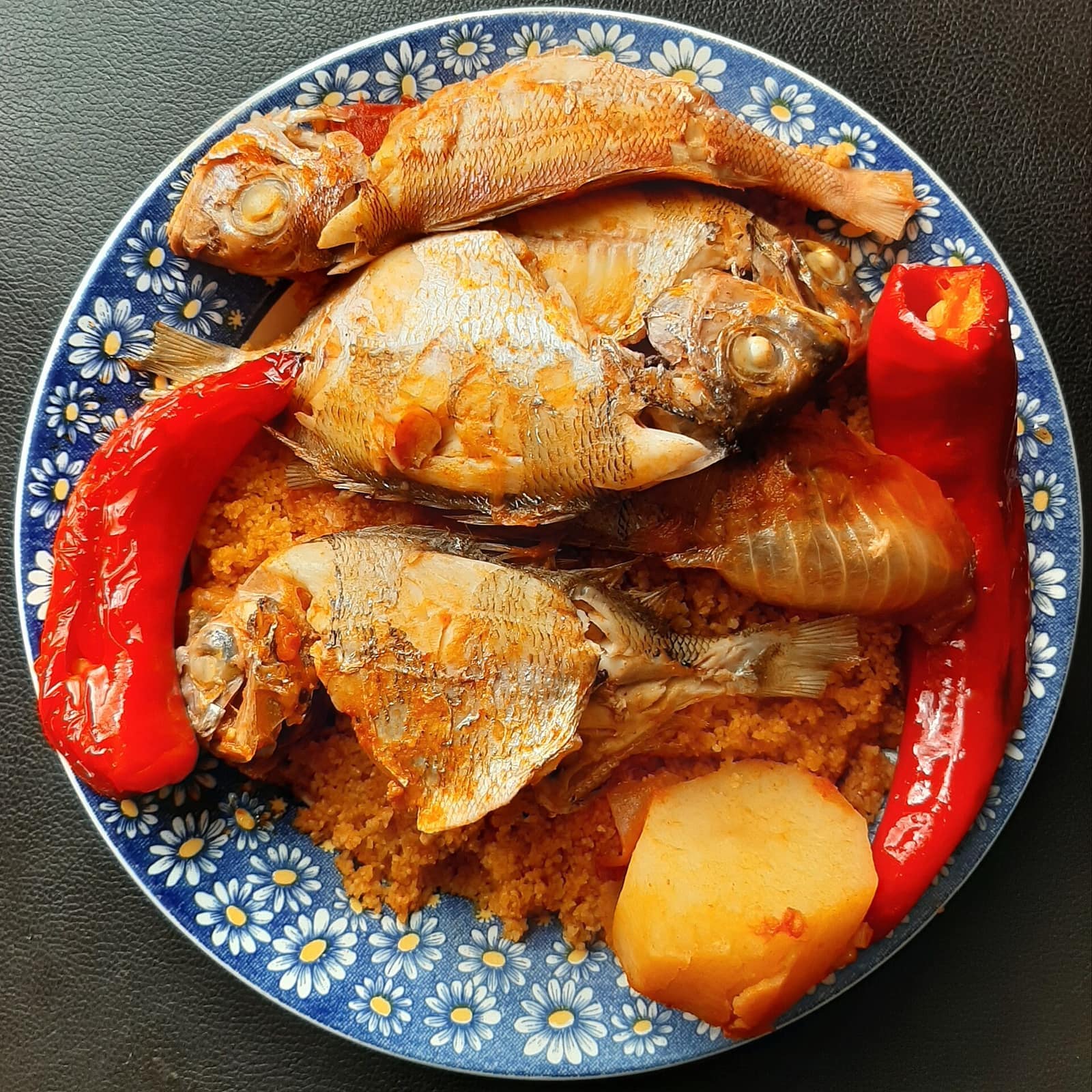 Couscous au poisson tunisien : poissons entiers, piments rouges et semoule safranée sur plat bleu