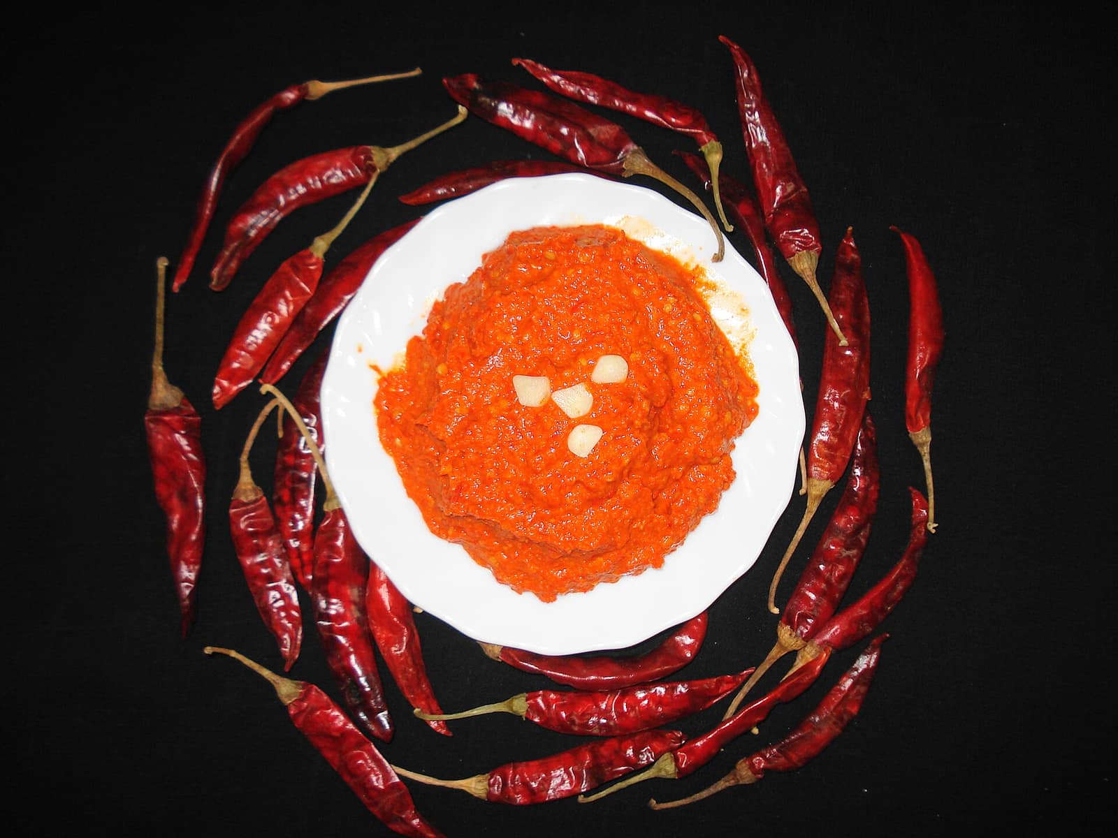 Harissa rouge pilée à l'ail, entourée d'une couronne de piments séchés
